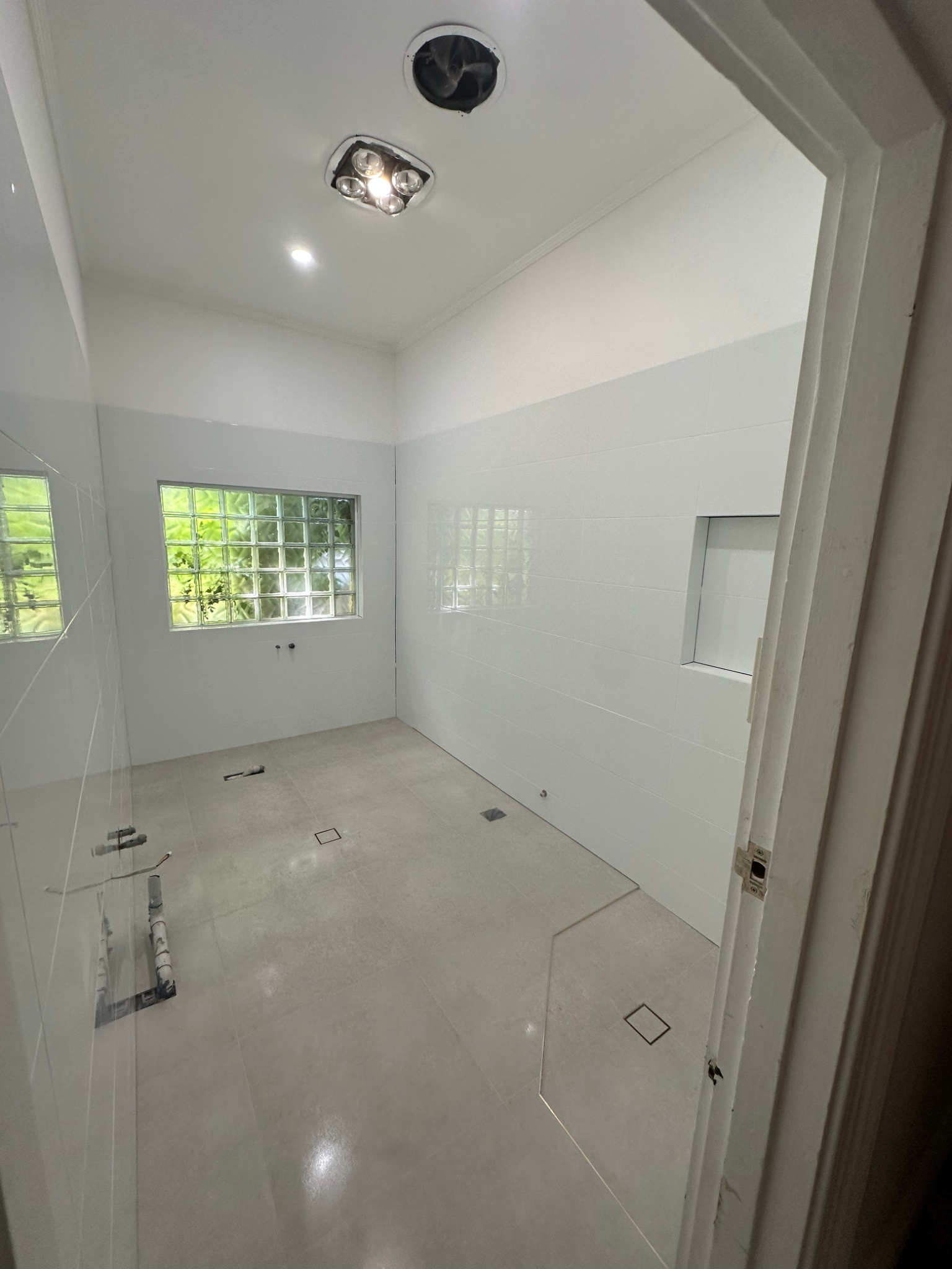 Polished bathroom featuring wooden vanity and large white wall tiles